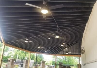 Underpass with ceiling fans and lights, leading to a gated entrance.