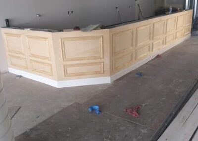 Unfinished interior of a building with a curved reception desk under construction and debris on the floor.