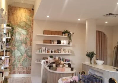 Interior of a boutique store with shelves of beauty products, a circular front desk, and a decorative stone wall.