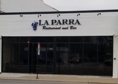 Exterior view of "la parra restaurant and bar" featuring a white facade, black windows, and a sign with the establishment's name.