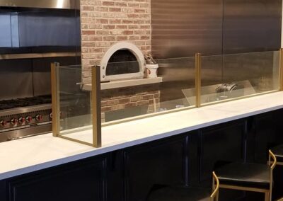 An empty modern restaurant interior with a brick pizza oven behind a bar with metal stools.