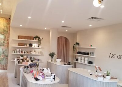 Interior of a minimalist beauty store, "art of pure," with curved display counters and products neatly arranged, under soft lighting.