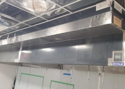 Large industrial air duct system installed above, with visible insulation and a digital control panel on the right.