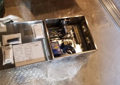 Open metal electrical cabinet displaying internal components and wiring, placed on a concrete floor.