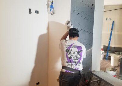 A worker applies joint compound to drywall in a construction site.