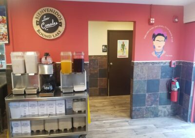 A beverage station with labeled dispensers in a restaurant featuring colorful walls and decorative elements including cultural artwork.