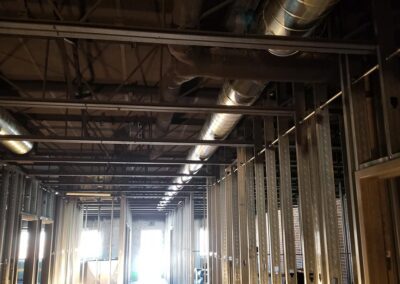 Interior of a building under construction with exposed metal studs, ductwork, and electrical conduits.