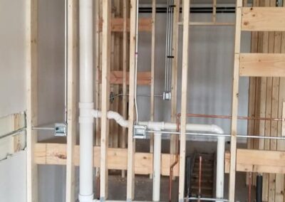 Exposed pipes and ductwork in the wall framing of a building under construction.