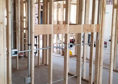 Interior construction site showing wooden stud framing and plumbing installations in an unfinished building.