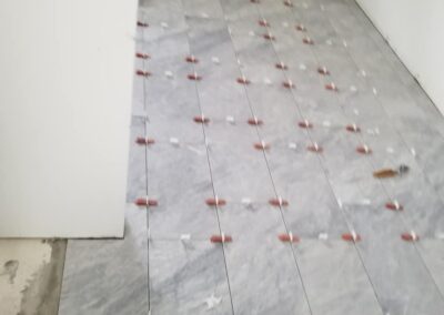 Newly laid gray tile flooring with spacer pegs, in a room under construction.