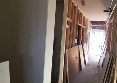 Interior of a building under construction showing exposed wooden studs and partially installed drywall.