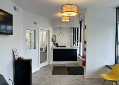 Modern hotel lobby with a black reception desk, white walls, pendant lights, and minimalist decor.